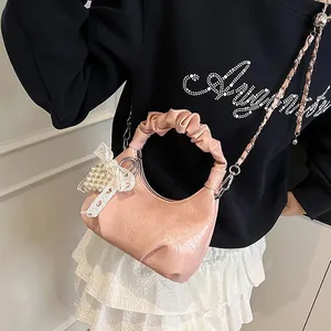 Pink pleated cloud bag with pearl bow pendant and metal chain strap on model