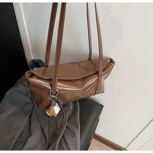 Close-up of brown polished leather shoulder bag with a unique baseball glove charm