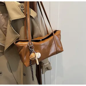 Close-up of caramel faux leather tote with baseball charms and CLEARON logo detail