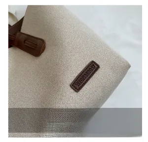 Close-up of durable beige canvas texture and brown leather details on the tote bag