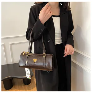 Detail der dunkelbraunen Schultertasche aus Leder mit goldenem Metalllogo und Beschlägen