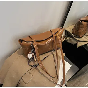 Detail of dark brown oil wax leather tote bag with unique baseball charm accessory