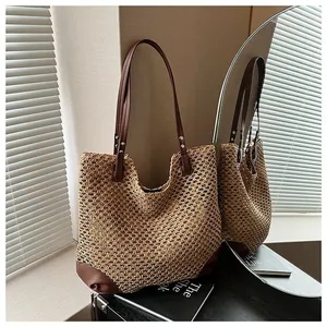 Handmade woven straw tote bag with brown leather base and slim straps for summer beach