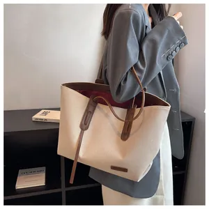 Canvas tote bag with leather trim detail shown in a stylish over-the-shoulder view