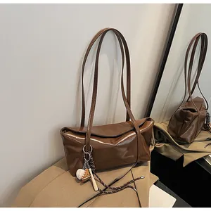 Close-up of vintage brown oil wax leather shoulder bag with a sporty baseball charm