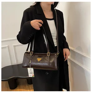 Nahaufnahme der braunen Ölwachs-Ledertasche mit Metall-Logo und glänzender Oberfläche