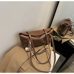Detail of brown oil wax leather shoulder bag with vintage flap and sports theme charms