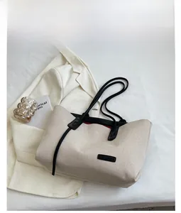Minimalist canvas tote bag with black leather straps styled with a blazer and book