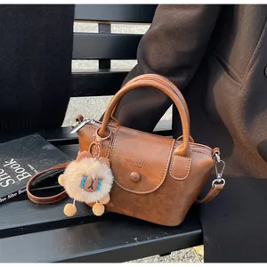 Detail of vintage brown leather bucket bag with top handle and plush bear charm decoration