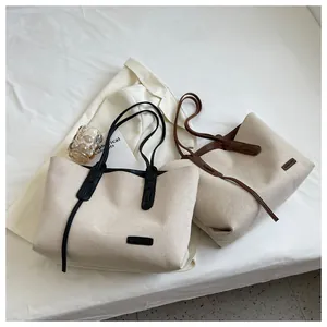 Detailed view of canvas tote bags with leather trim and brand label on a lifestyle setup