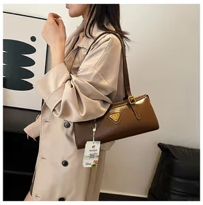 Detailansicht der braunen Lackleder-Achseltasche mit goldenem Dreieckslogo und Gurt