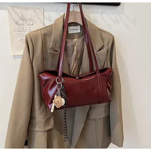 Detail of burgundy oil wax leather tote with baseball charm and embossed logo detail