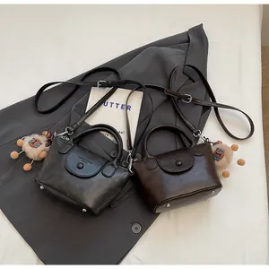 Close-up of minimalist leather crossbody bucket bags with plush animal charm details