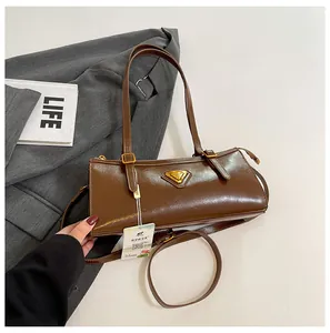 Detailansicht der dunkelbraunen rechteckigen Tasche mit goldenem Dreieckslogo und Glanz