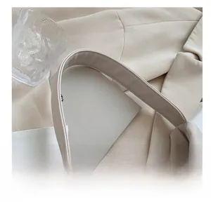 Detail of soft cream PU leather handbag with wide pleated handle and neat stitching
