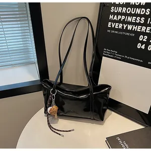 Detail of glossy black leather tote bag with biscuit pendant and sleek modern finish