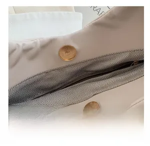Close-up of durable magnetic clasp and twill fabric lining on beige cloud bag