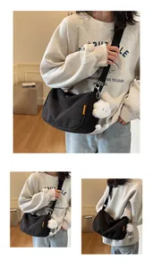 Close-up of black corduroy dumpling bag with cloud charm and adjustable strap