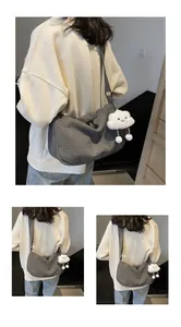 Detail of grey corduroy dumpling bag with adjustable strap and plush cloud charm accessory