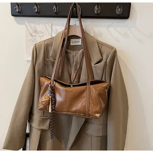 Detail of glossy brown wax leather tote with logo embossing and heart pendant