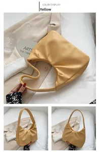 Detail view of a yellow ruched dumpling bag in crescent shape with a matching top handle