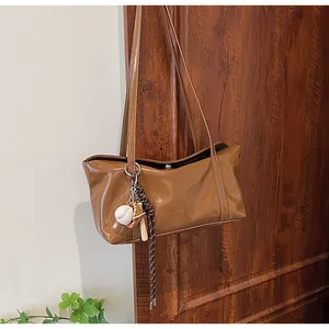 Brown waxed leather shoulder bag with CLEAROK logo and decorative baseball theme pendant