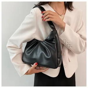 Detail of black pleated cloud bag texture shown on a white blazer shoulder