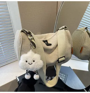 Detail view of beige corduroy crossbody bag with wide strap and cloud plush charm