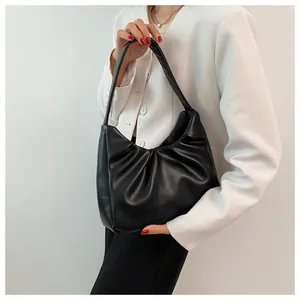 Detail of a black pleated hobo bag with sleek synthetic leather and shoulder strap style