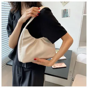 Detail of a creamy off-white pleated cloud bag showing soft PU leather texture and shoulder strap