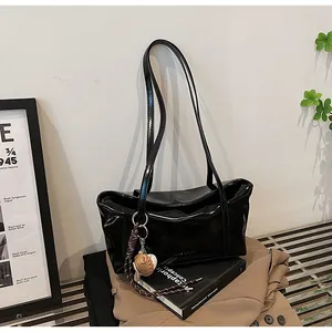 Chic black glossy leather tote bag on metal bench with stylish baseball charm detail