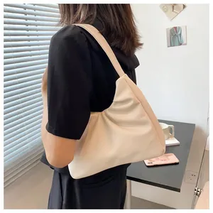Close-up of a beige pleated cloud bag worn as a shoulder bag showing soft leather detail