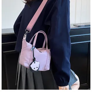 Side view of lavender nylon crossbody dumpling bag with wide fabric strap and cute charm