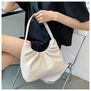 Detail of off-white pleated hobo bag shown as an underarm shoulder bag on a model