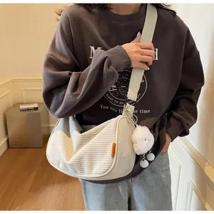 Detail view of cream corduroy crossbody bag with light green strap and plush cloud charm