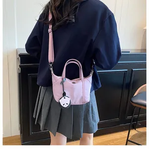 Back view of a mini lavender nylon tote bag with a cute panda charm on a model