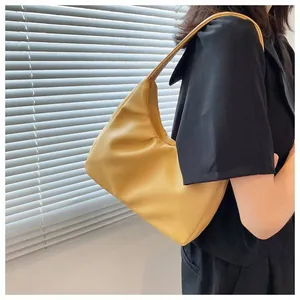 Fashionable bright yellow pleated cloud shoulder bag worn by model against a white shutter