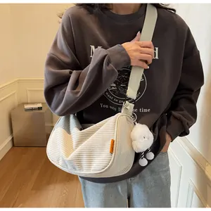 Detail of cream corduroy crossbody bag with soft plush cloud charm on strap