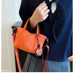 Orange crossbody dumpling bag with metal logo and cute blue cartoon animal pendant