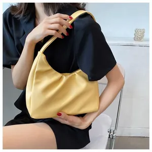 Detail of a bright yellow cloud-shaped faux leather shoulder bag worn by a model