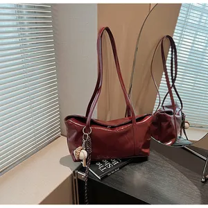 Detail view of burgundy glossy leather shoulder bag with creative baseball charm