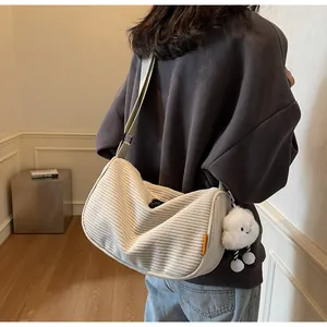 Detail of off-white corduroy dumpling bag with cloud plush charm and adjustable strap
