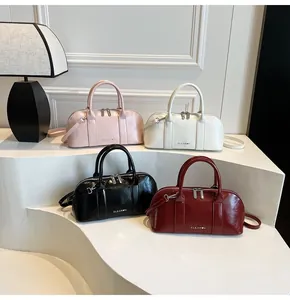 Bolsos Boston en cuatro colores sobre un pedestal blanco con luz suave de oficina