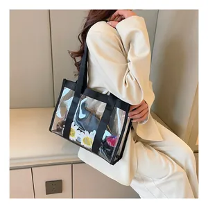 Close-up of a clear PVC tote bag with black canvas straps showing detailed daily contents