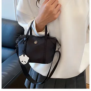 Detail of black nylon dumpling bag with adjustable strap and cute panda charm accessory