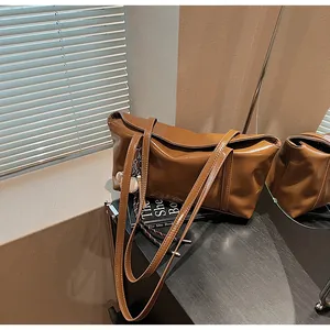 Detailed view of a brown glossy leather tote bag with long shoulder straps and charms