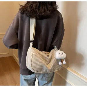 Detail of cream corduroy dumpling bag featuring adjustable strap and plush cloud charm