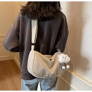 Detailed back view of a beige corduroy crossbody bag with a plush cloud pendant on a model