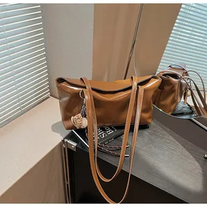 Close-up of brown polished leather shoulder bag with metallic chain and embossed logo