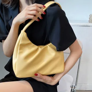 Fashionable bright yellow pleated cloud hobo bag worn as an underarm shoulder bag